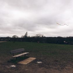 Trees on field against cloudy sky