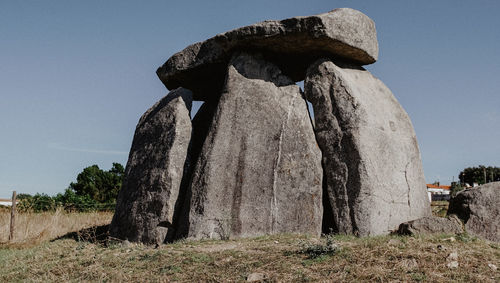 Stone sculpture on field against clear sky