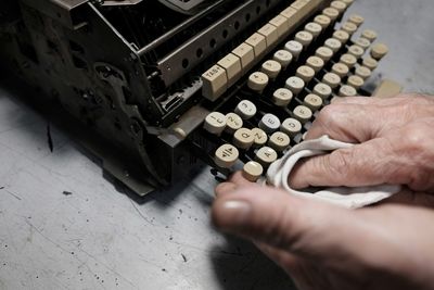 Close-up of person cleaning typewriter on table