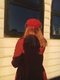 Rear view of woman standing against wall