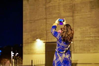 Rear view of woman photographing at poliesportiu municipal del centre in lhospitalet de llobregat during night