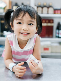 Cute girl looking away while leaning on table at restaurant