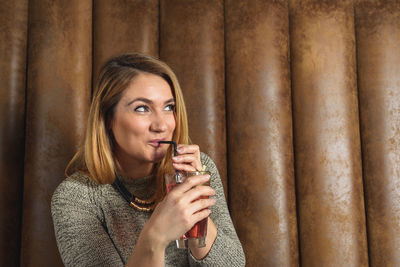 Adult woman sipping cocktail in bar