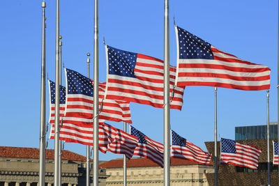 Low angle view of american flags against clear blue sky