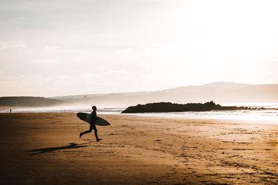 Silhouette man on beach against sky during sunset