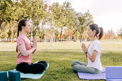 Two young women in the park doing yoga. exercising outdoors, healthy lifestyle