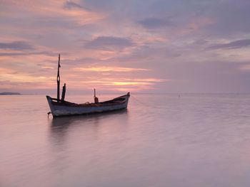 Boat in sea against sky during sunset