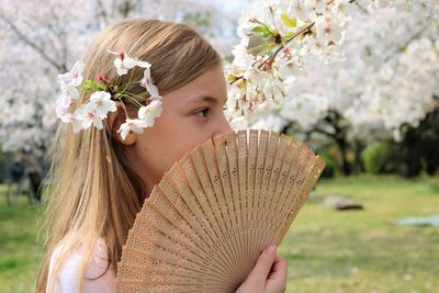 Portrait of young woman holding cherry blossom
