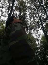 Low angle view of woman standing amidst trees in forest