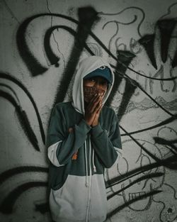 Full length of man standing against graffiti wall