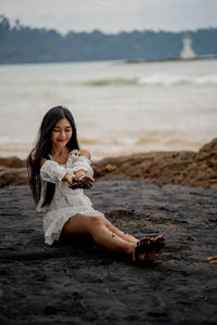 Portrait of woman sitting on shore at beach