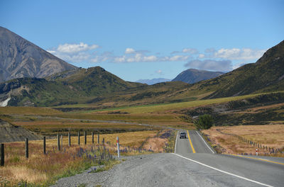 Road leading towards mountains against sky