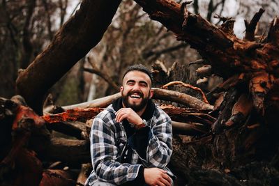 Cheerful man sitting on fallen trees