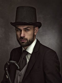 Portrait of young man wearing hat against black background
