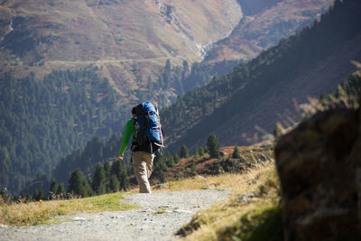 Rear view of male hiker with backpack walking at mountain