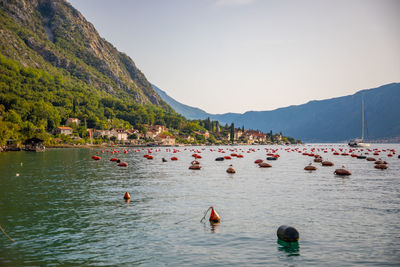 Group of people swimming in lake against mountain range