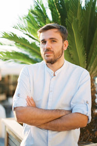 Portrait of young man standing against trees