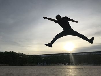 Low angle view of silhouette man jumping against sky during sunset