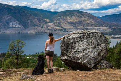 Rear view of man standing on rock looking at mountains