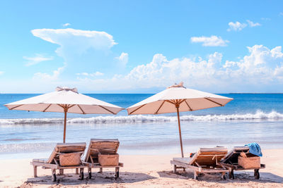 Beach with chairs. sun beds and umbrella at bali coast. luxury beach background 