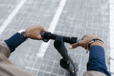 Hands of man holding handlebar of e-scooter