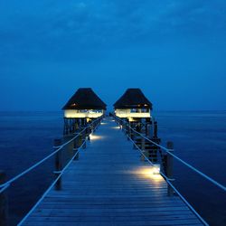 Pier over sea against blue sky ar night