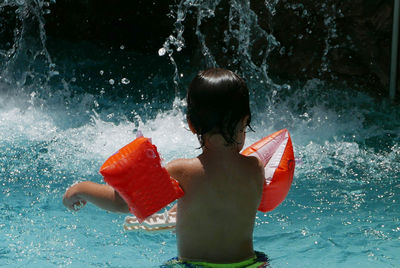 Child splashing water in swimming pool