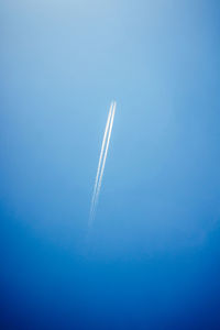 Low angle view of airplane flying over blue background