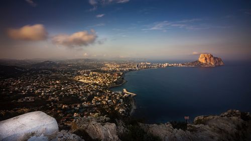 Aerial view of city by sea against sky