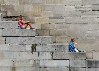 Side view of couple sitting on wall