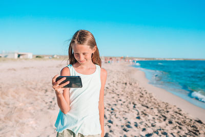 Young man using mobile phone while standing on beach