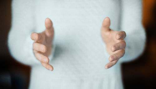 Midsection of man gesturing while standing at home