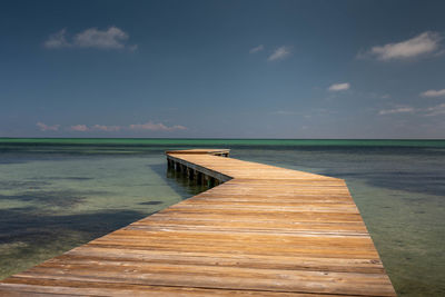 Wooden pier on sea against sky