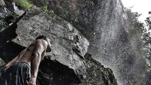 Low angle view of man standing at waterfall 
