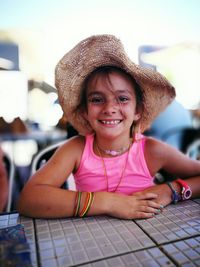 Portrait of happy girl wearing hat at table