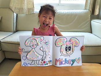 Happy girl looking away while standing on sofa