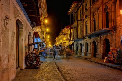 People on street amidst buildings at night