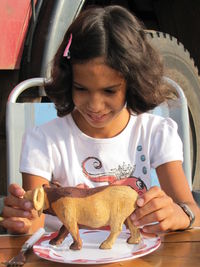 Smiling girl playing with toy animal on plate at farm