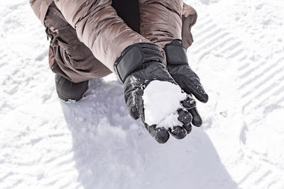 Low section of man holding ice in hand outdoors