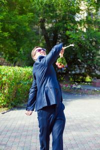 Young man troughing bouquet outdoors