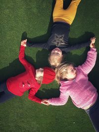 3 young girls hold hands whilst lying on the ground in a circle