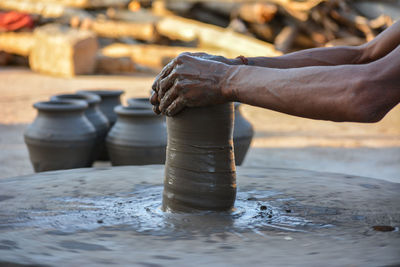 Hands working on pottery wheel and making a pot