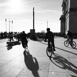 People on bicycle in city against sky