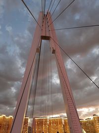 Low angle view of suspension bridge against cloudy sky