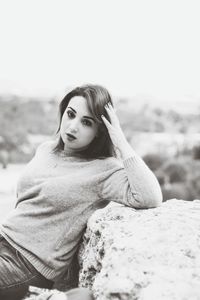 Portrait of young woman leaning on rock