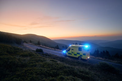 Ambulance car of emergency medical service mountain road against sunrise. moody sky with copy space. 