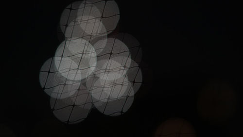 Low angle view of illuminated lighting equipment against black background