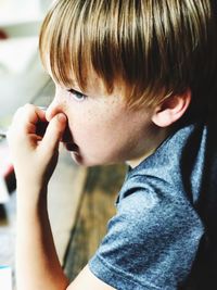 Close-up of boy holding nose