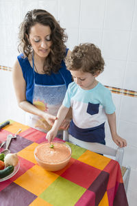 Woman preparing food while standing with son