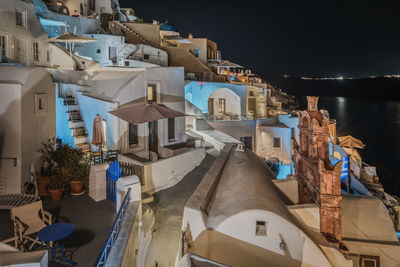View of oia village at night with whitewashed houses illuminated, santorini, greece
